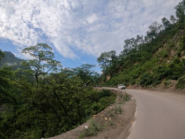istock Scenic mountain road with lush greenery and a partly cloudy sky. 2175969247