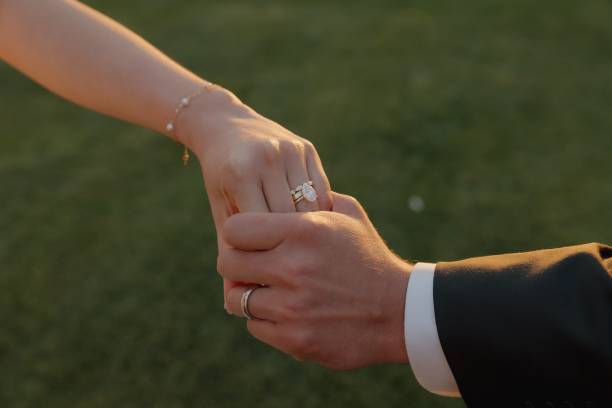 istock Couple Holding Hands with Wedding Rings at Sunset 2175969336
