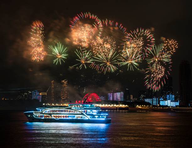 Cruise ship with fireworks display over city skyline at night.