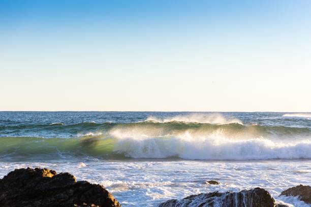 istock Waves crashing on a rocky coastline under a clear blue sky 2175969651
