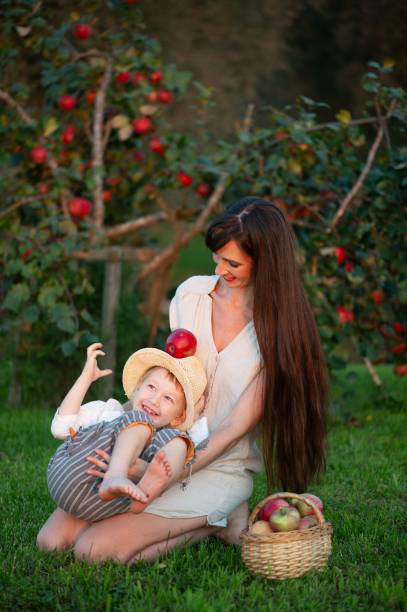 9 month old baby girl in a green knitted sweater enjoying an apple on a sunny day