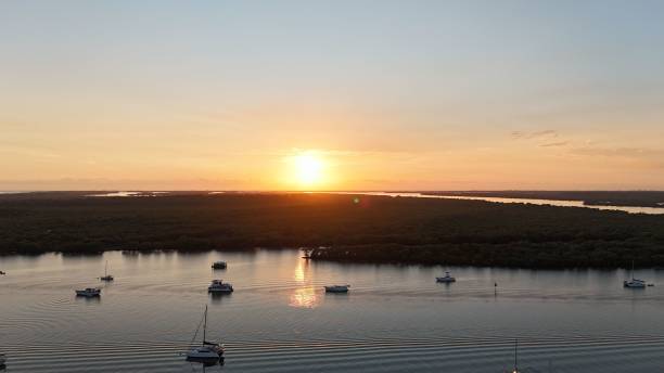istock Sunset over calm river with boats and forest horizon. 2175971892