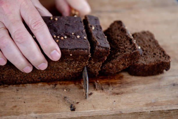 istock The man cuts whole-wheat rye bread on a wooden cutting board. 2175972432