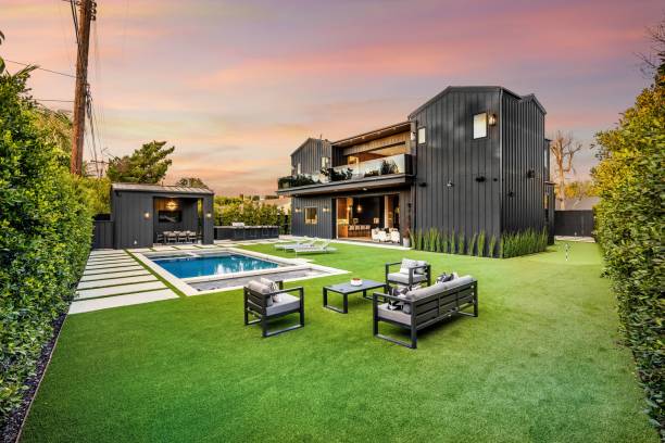 Modern luxury home with a spacious backyard and pool at sunset.