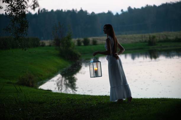 istock Woman with Lantern by Lakeside at Dusk 2175977602