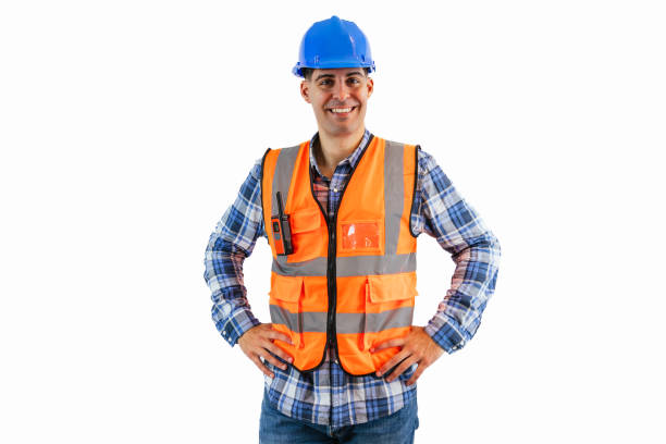 istock Construction worker in blue helmet and orange safety vest smiling, hands on hips white background 2175978435