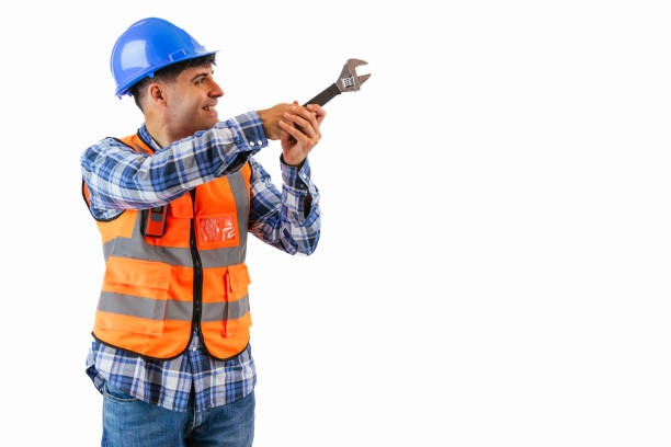 copyspace construction worker is tightening a screw using a wrench while wearing an orange reflective vest and a blue safety helmet. showcases the precision and dedication of workers white background