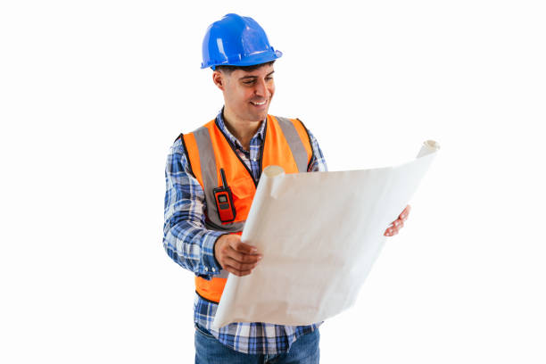 istock Smiling engineer holding construction plan wearing orange vest and safety helmet white background 2175978633