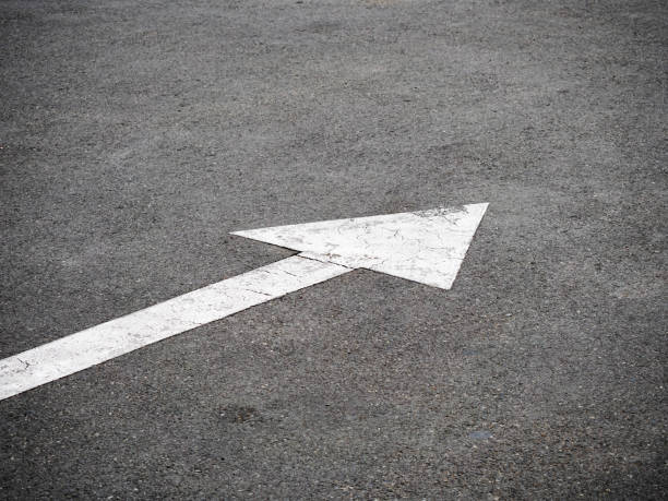 White arrow sign on asphalt road. Traffic symbol on street
