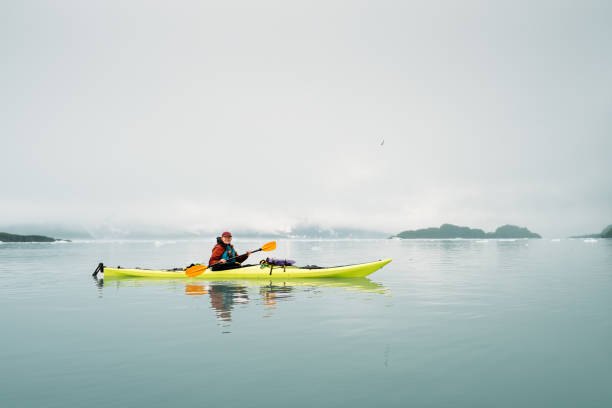 Mature mother and teen daughter enjoy morning kayaking and canoeing in rural Bamfield, British Columbia, Canada.