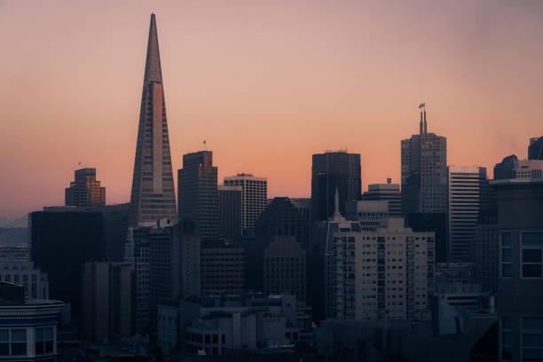 San Francisco, California skyline at sunset. On the  middle is the The Transamerica Pyramid the tallest skyscraper in the San Francisco skyline. In the background is the Francisco–Oakland Bay Bridge. San Francisco is a popular tourist destination known for its landmarks including the Golden Gate Bridge and cable cars.