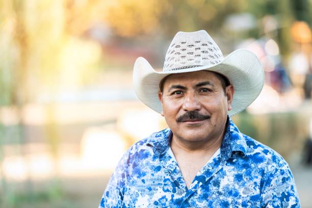 Smiling mature hispanic man looking at the camera wearing a cowboy hat