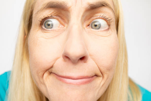 A close up of a woman in her 50s making a funny face looks to the side with a perplexed expression.
