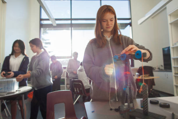 Teenage girl in high school classroom making physics construction science engineering technology mathematics STEM project