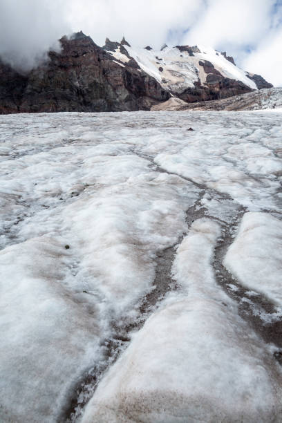 istock A vast glacier stretches out before a towering mountain, its surface cracked and textured. 2175997788