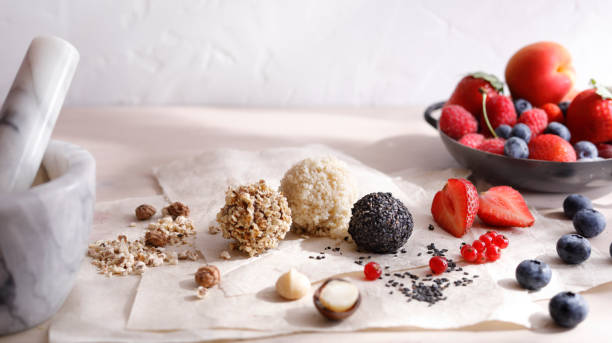 Raw coconut balls placed in a halved coconut on a rustic wooden surface. Healthy vegan snack made with natural ingredients and no added sugar.
