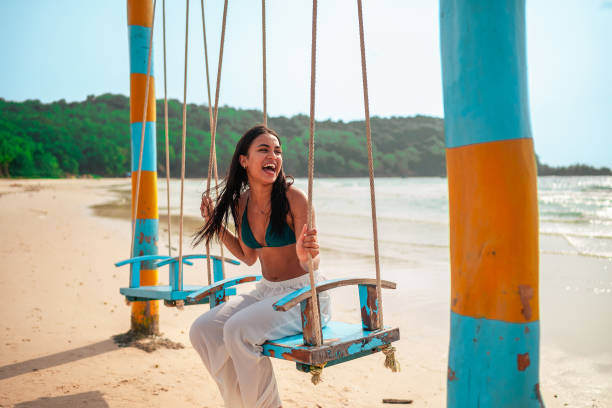 Joyful Hispanic Woman Enjoying Swing on Beach