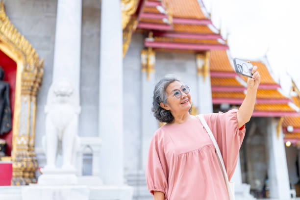 istock Asian elderly woman using smartphone taking selfie during travel Buddhist temple. 2176011579