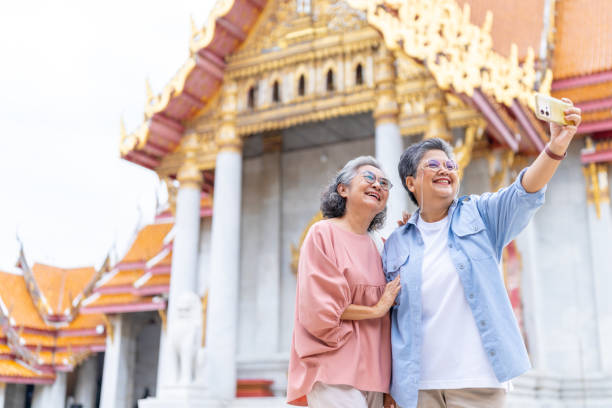 istock Asian elderly woman using smartphone taking selfie during travel Buddhist temple. 2176011584