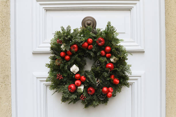 Christmas wreath with branches and red apples on a white door
