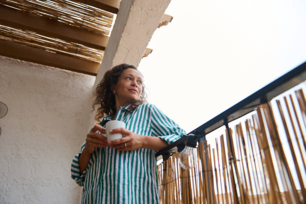 istock Relaxed woman enjoying coffee on a sunny balcony 2176024975