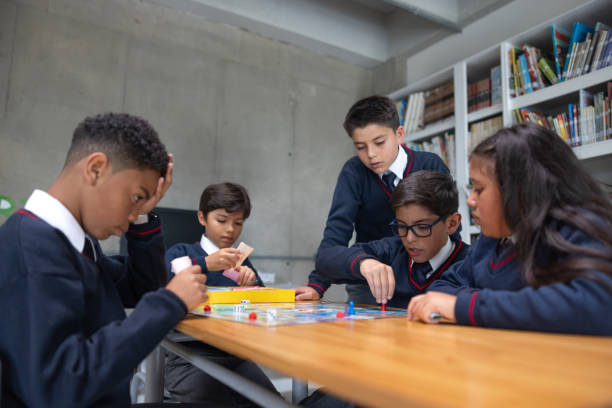 Latin American group of elementary students playing board games in the classroom â education concepts