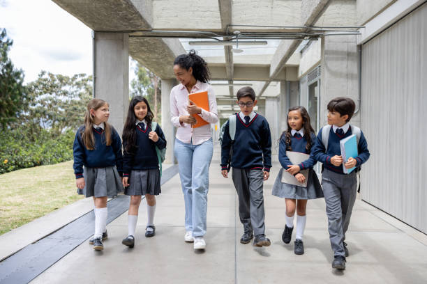 istock Happy school teacher walking in the corridor with a group of elementary students 2176025191