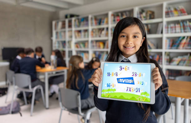 Portrait of a happy Latin American schoolgirl learning mathematics using an app on a digital tablet