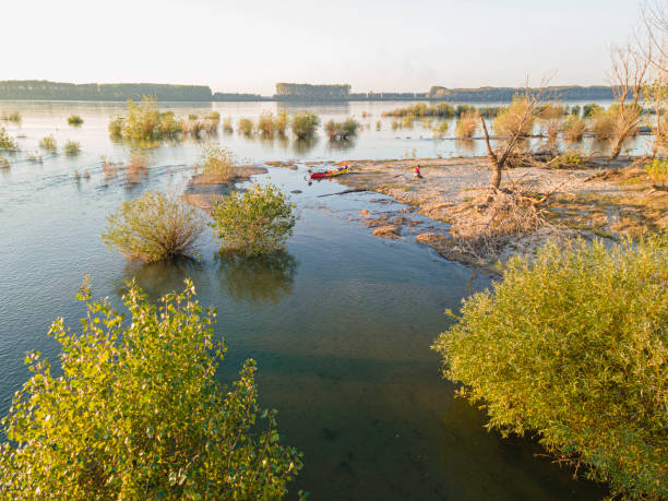 Waterborne adventure. Paddling & ecotourism. Mature man connecting with nature, just moored his kayak on an island in Danube River. Aerial view