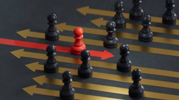 istock 3d illustration of many black pawns going on the same direction and a RED one going on the opposite side.3D rendering on black background. 2176040495