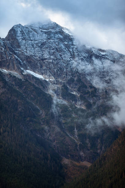 A dark and cold Autumn morning in North Cascades National Park, Washington state, USA. Tall mountains, forests and emerald lake water shows a classic Pacific Northwest scene in the fall time.