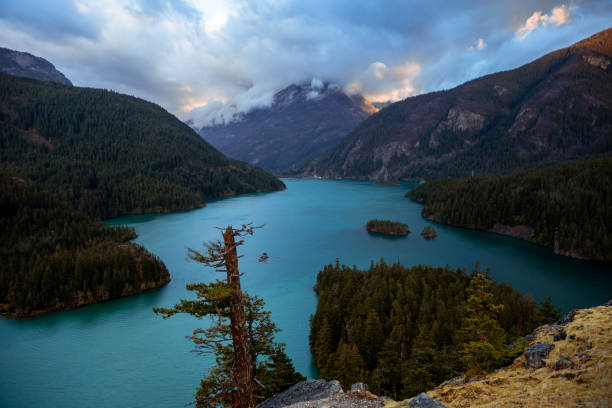 A dark and cold Autumn morning in North Cascades National Park, Washington state, USA. Tall mountains, forests and emerald lake water shows a classic Pacific Northwest scene in the fall time.