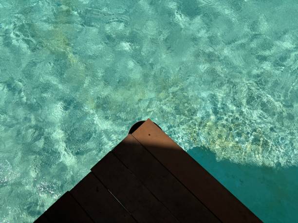 istock Crystal-clear turquoise water with rippling reflections seen from above a wooden deck 2176047162