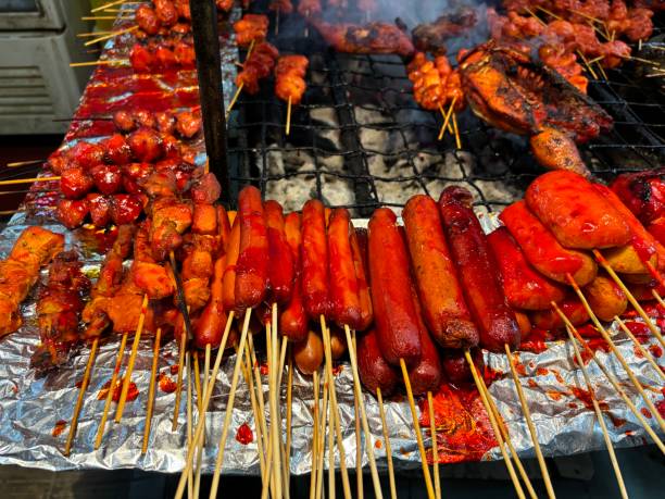 Stack of juicy meat and sausage skewers sizzling on a smoky grill