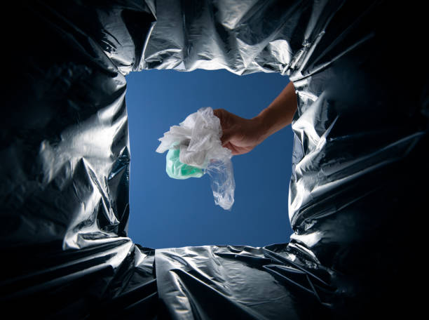 istock World Environment Day concept. Hand holding plastic and paper waste into the garbage bin from inside 2176047947