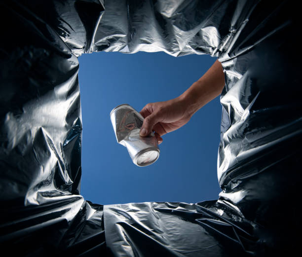 istock World Environment Day concept. Hand holding aluminum can waste into the garbage bin from inside 2176047951
