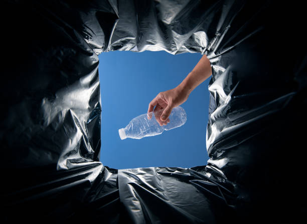 istock World Environment Day concept. Hand holding plastic bottle waste into the garbage bin from inside 2176047966