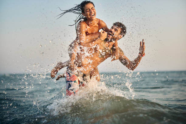 istock Cheerful couple having fun while splashing and piggybacking at sea. 2176060463