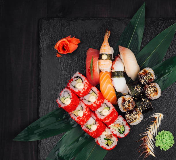 istock Sushi set lying on green leaves on black stone plate 2176061745