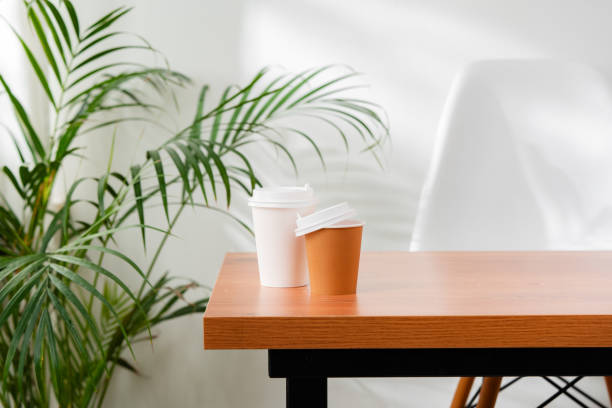 istock A disposable coffee cup on a wooden table beside a leafy plant 2176061758