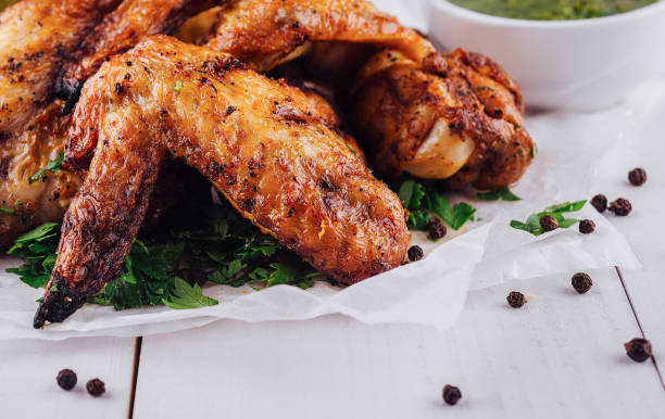 istock Delicious roasted chicken wings lying on white paper on white table 2176061807