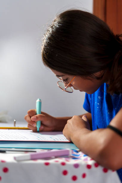 istock Focused Girl Studying and Writing in Notebook with Pencil at Home Desk 2176072288