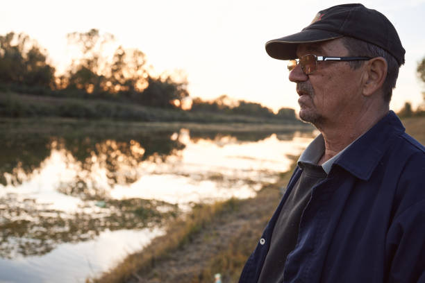 Enjoyable sunset on a river. Senior man fishing.