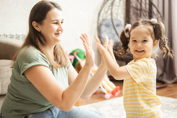 istock mom is having fun playing with her little daughter sitting on the floor. 2176078024