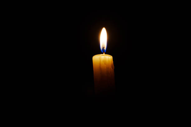 istock Close-up single candle burning on dark black background 2176078405