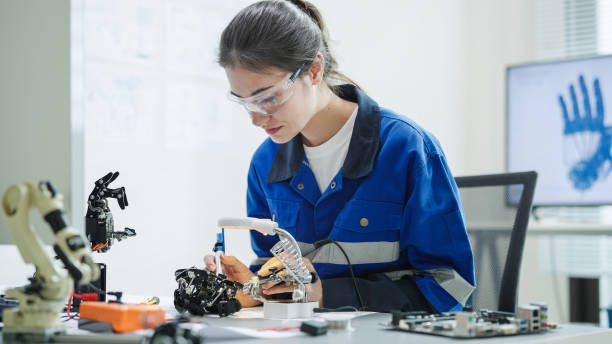 istock White woman engineer developer wearing safety protective goggles with blue work jacket is soldering intricate robotic components on a circuit board or an electronic device workshop in a laboratory room 2176081880