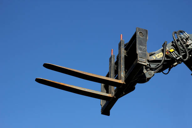 Excavator machine with a construction forklift attachment rising high in the sky