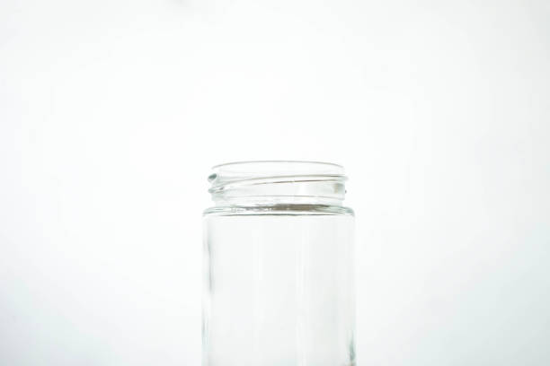 An empty clear glass is placed on a wooden patterned table isolated on a white background