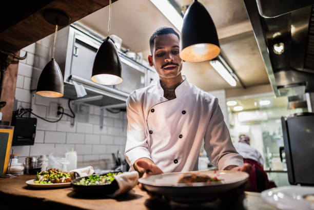 istock Young chef preparing food on a plate at restaurant kitchen 2176094097