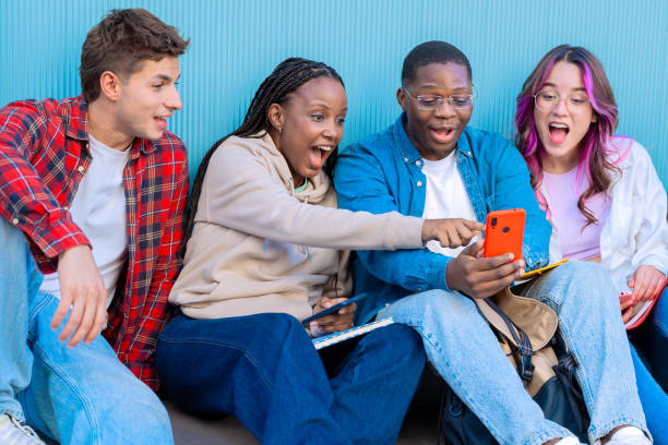 istock A group of diverse young people smiling sitting outdoors using smart phones 2176094254